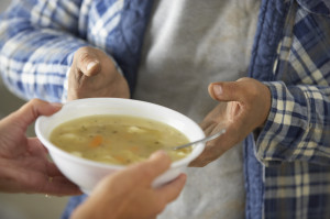 Hands of Homeless Man Receiving Bowl of Soup